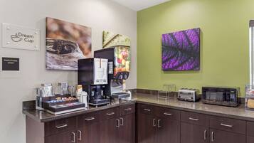 Una kitchenette equipada con cafetera, tostadora y microondas. Se observan armarios y una encimera.