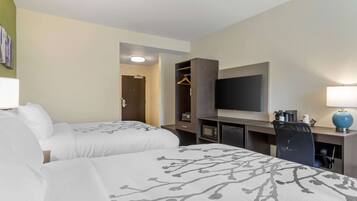 Une chambre d’hôtel avec deux lits, un bureau, une télévision et une armoire.