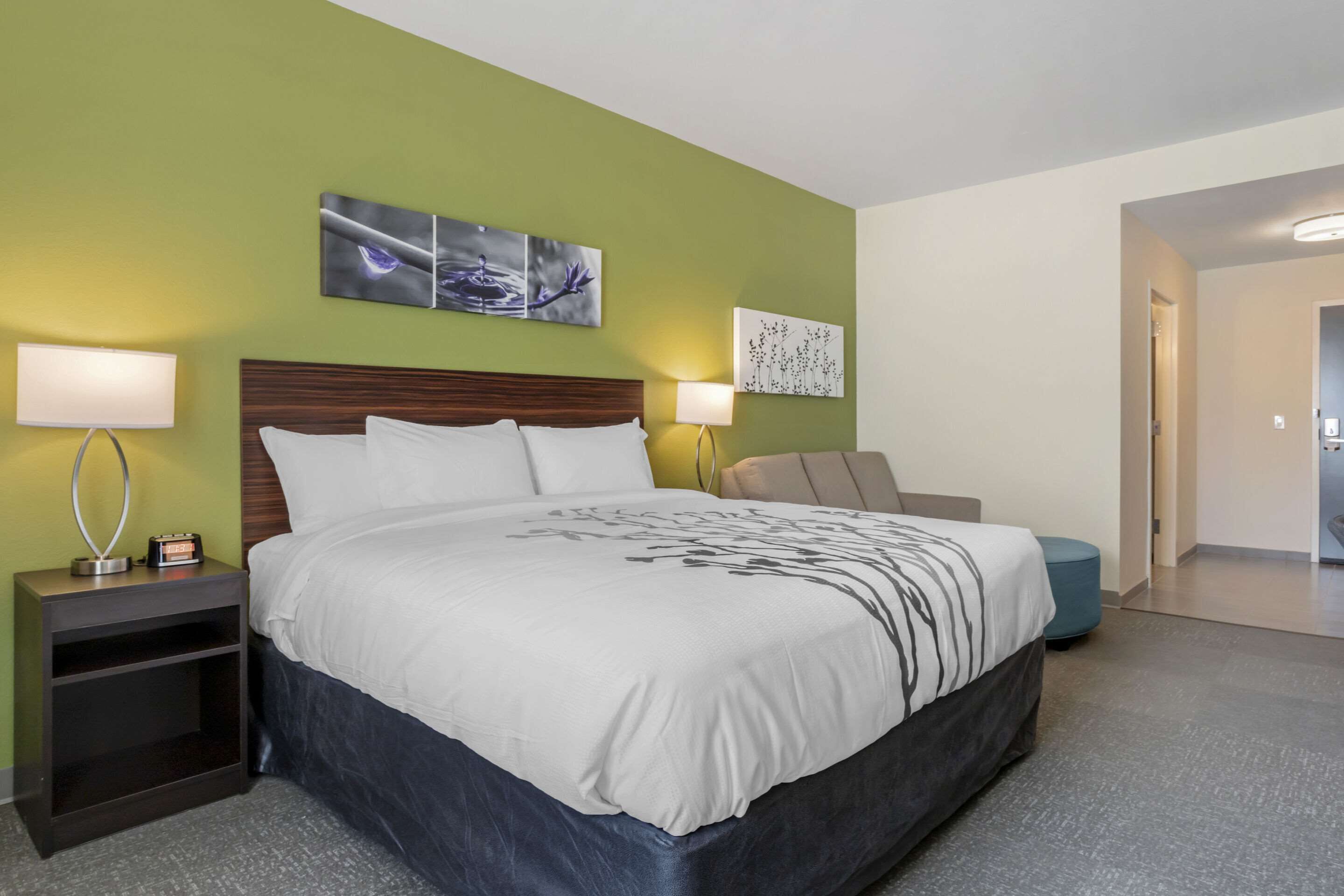 A hotel room with a large bed, two bedside tables with lamps, and artwork on the walls.
