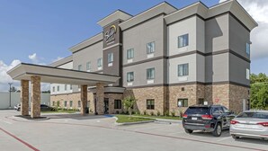 Ein Sleep Inn & Suites Hotel mit überdachtem Parkplatz, mehreren Etagen und blauem Himmel.