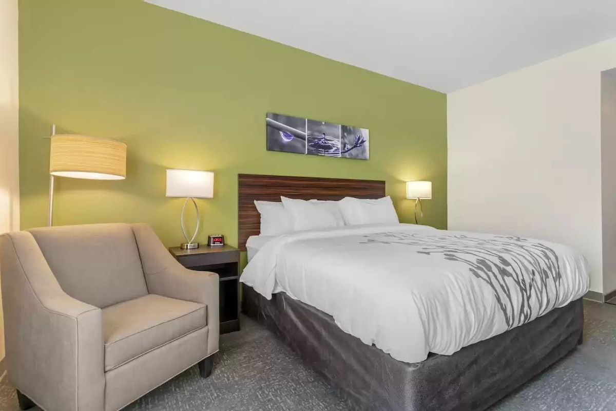 A hotel room with a bed, a chair, and two bedside lamps.