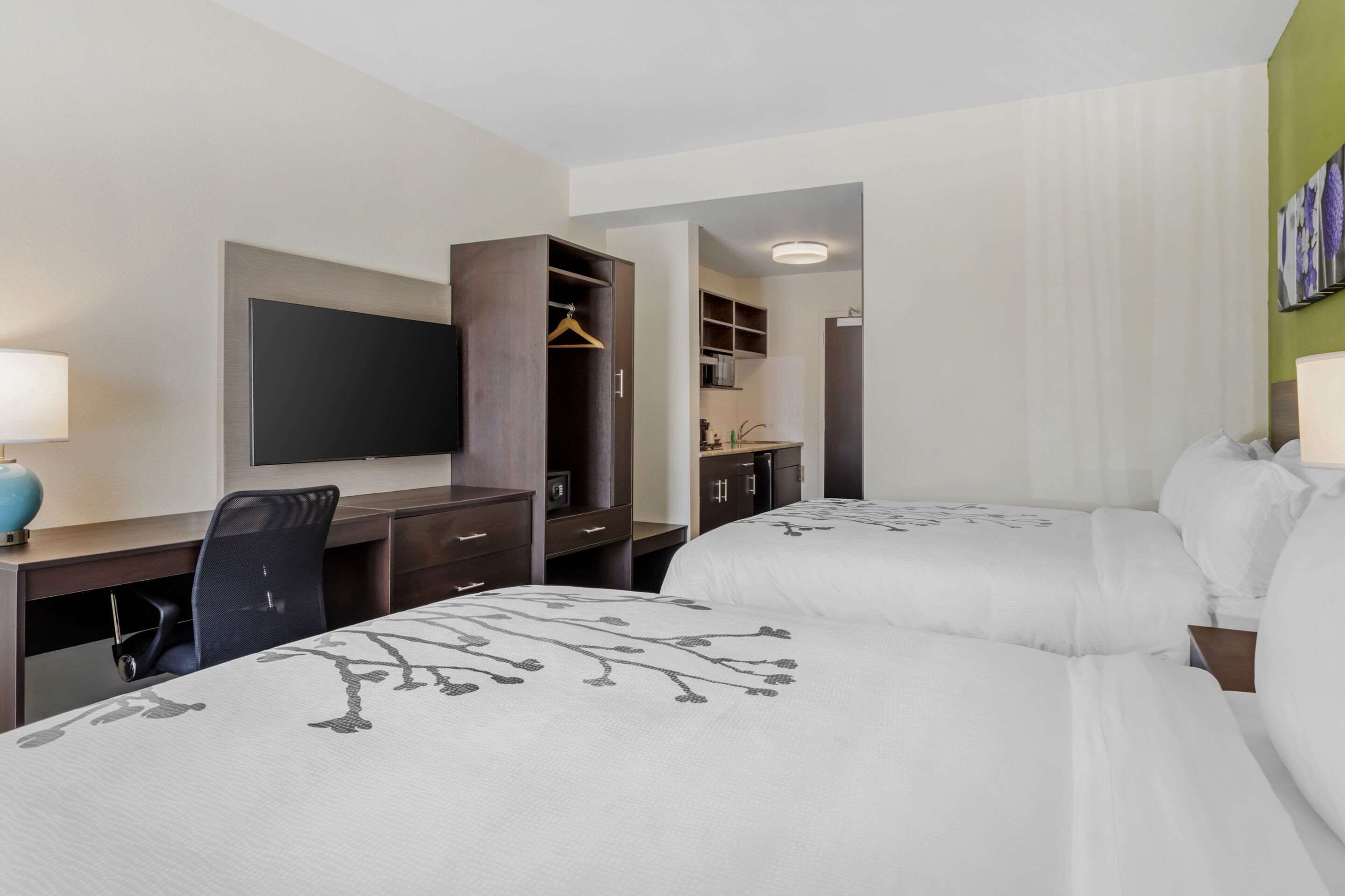 A hotel room with two beds, a desk, a TV, and a wardrobe.