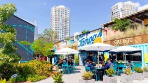 An outdoor seating area with tables and chairs, a mural, and a building with a sign that reads "Gallito."