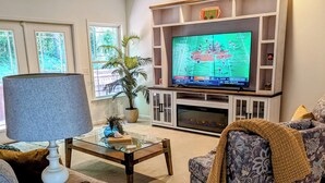 Un salon équipé d’un téléviseur, de sièges, d’une table basse et d’un ventilateur de plafond.