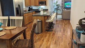 Une cuisine moderne avec des meubles en bois, un réfrigérateur en acier inoxydable, un four à micro-ondes et un coin repas comprenant une table et des chaises.