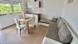 A compact living space with a kitchenette, dining area, and seating area. - Holiday apartment mit Klimaanlage und Balkon (Jadranovo)