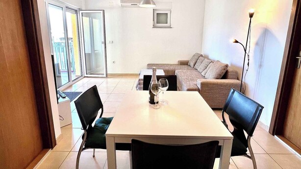 A modern living room with a dining table, two sofas, and a large window. - Holiday apartment modern and well equipped (Jadranovo)