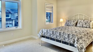 A bedroom with a bed, a window, and a lamp. - 4-Bedroom House (Caledonia)
