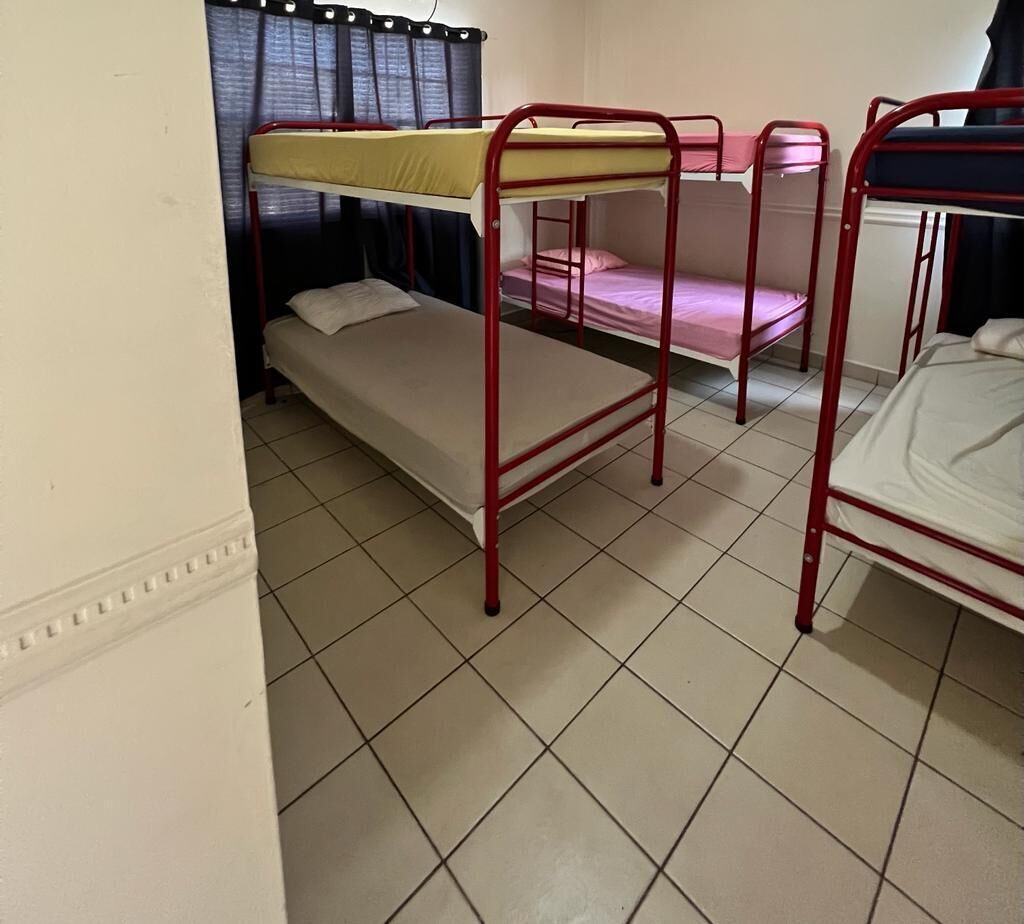 A dormitory room with bunk beds and a tiled floor.