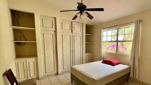 A bedroom with a bed, a ceiling fan, a window with curtains, and built-in wardrobes. - SAM Travel Managua, Centrico de la Ciudad Capitalina (Managua)