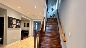 A wooden staircase with a handrail, leading to a room with a blue wall and decorative mirrors. - Cozy 5 Bedroom House in Mississauga, On  (Mississauga)