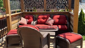 A covered outdoor seating area with wicker furniture and red cushions. - Cozy 5 Bedroom House in Mississauga, On  (Mississauga)