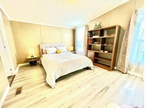 Cozy retreat with a large bed, nightstand, and bookshelf.