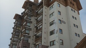 A multi-story hotel with a stone facade and wooden balconies. - Amplio Departamento con Vistas a la Montaña, ¡con Ski-in y Ski-out ! (Santiago)