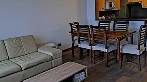 A modern living room with a sofa, a wooden coffee table, and a dining table with chairs. - Amplio Departamento con Vistas a la Montaña, ¡con Ski-in y Ski-out ! (Santiago)