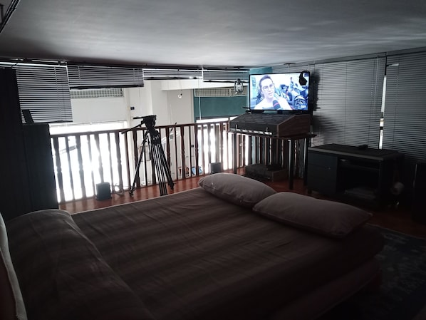 A room with a bed, a desk, a television, and a balcony.
