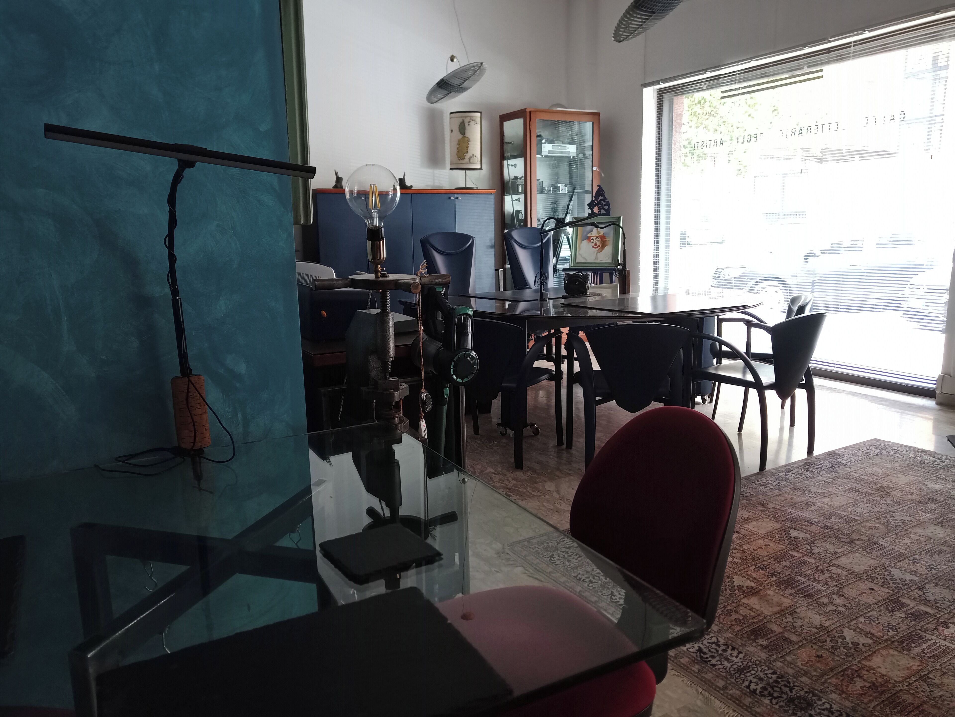 Una habitación con una mesa de vidrio, sillas, un escritorio y un ventanal grande.