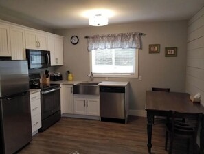 Compact kitchen with modern appliances, white cabinetry, and a dining area.