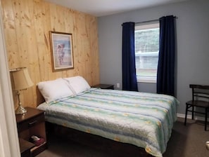 Cozy retreat with a single bed, framed picture, and a small table and chair.