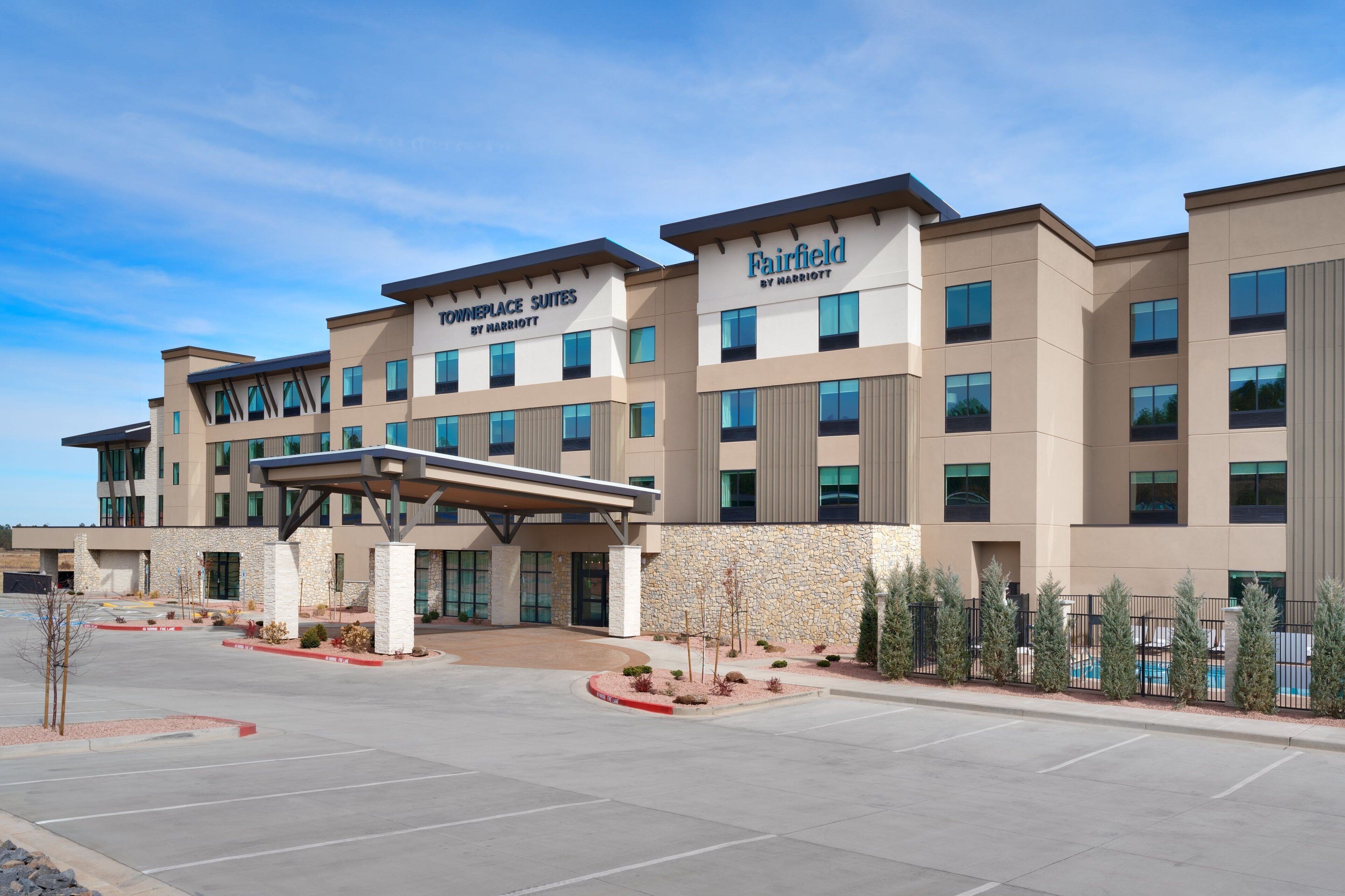 A hotel with a modern design, featuring a covered entrance and a pool area.