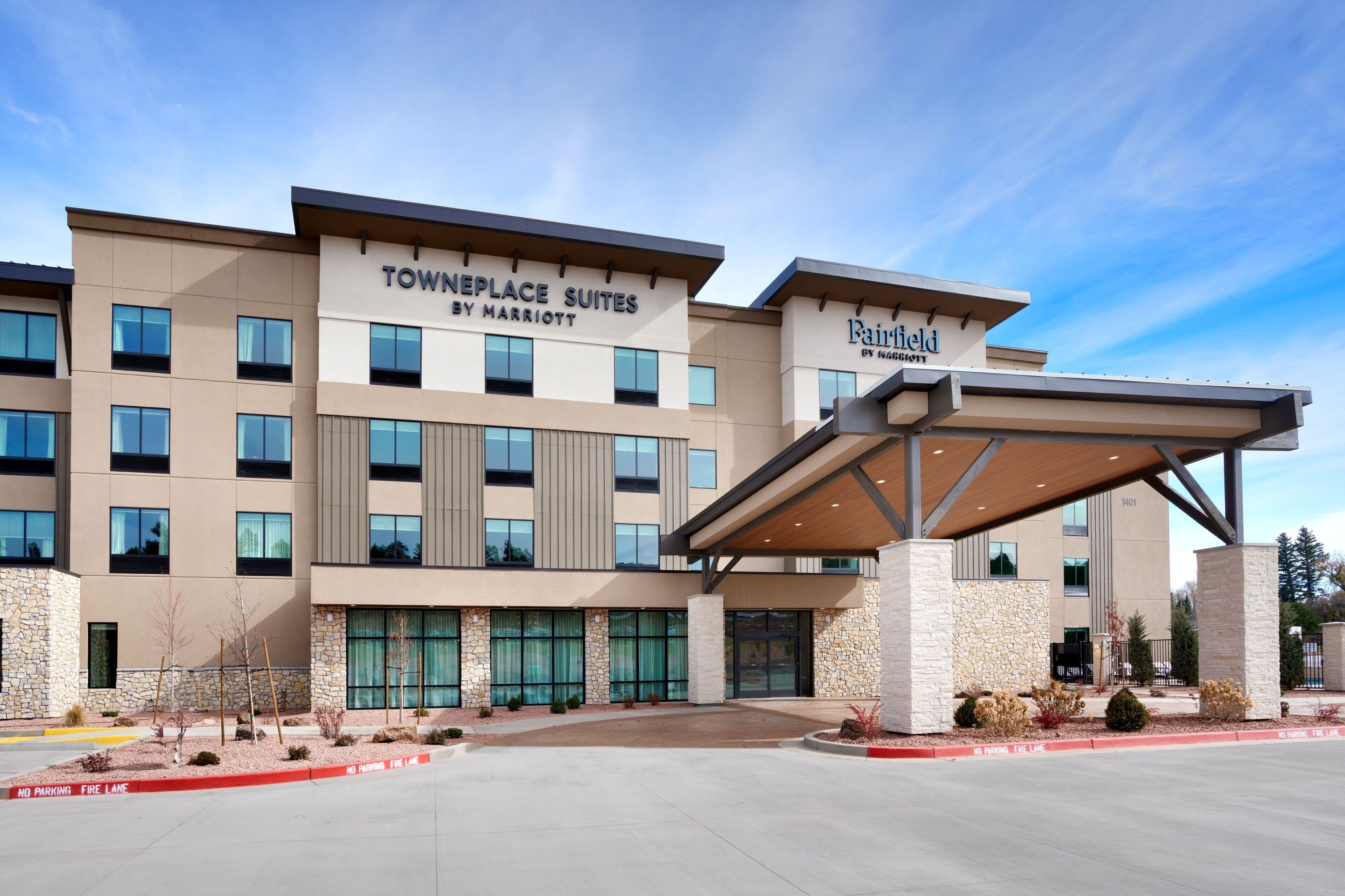 A hotel with a modern facade, named "Tonnelle Place Suites by Marriott," featuring a covered entrance and a stone facade.