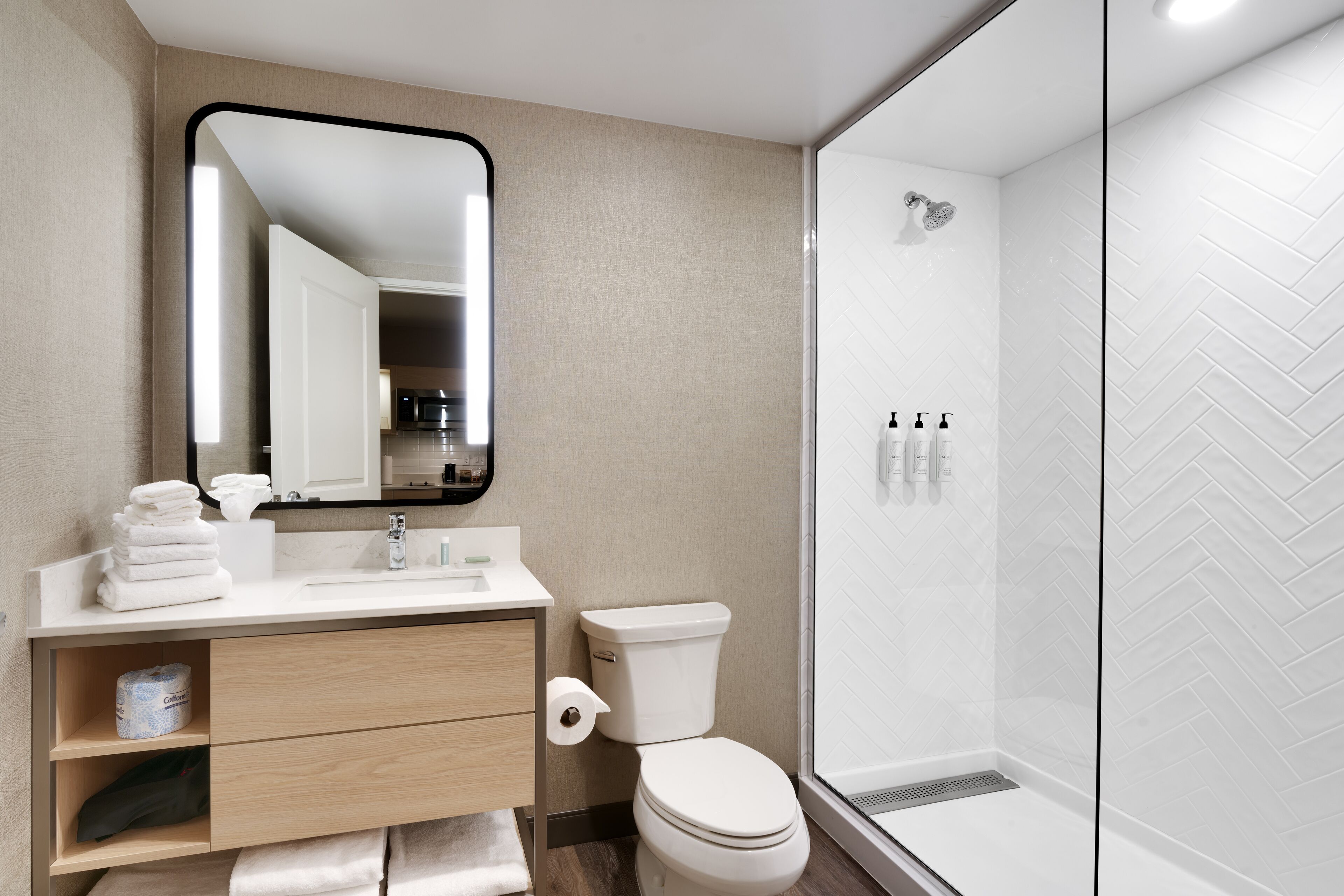 Un baño moderno con inodoro, lavamanos y ducha.