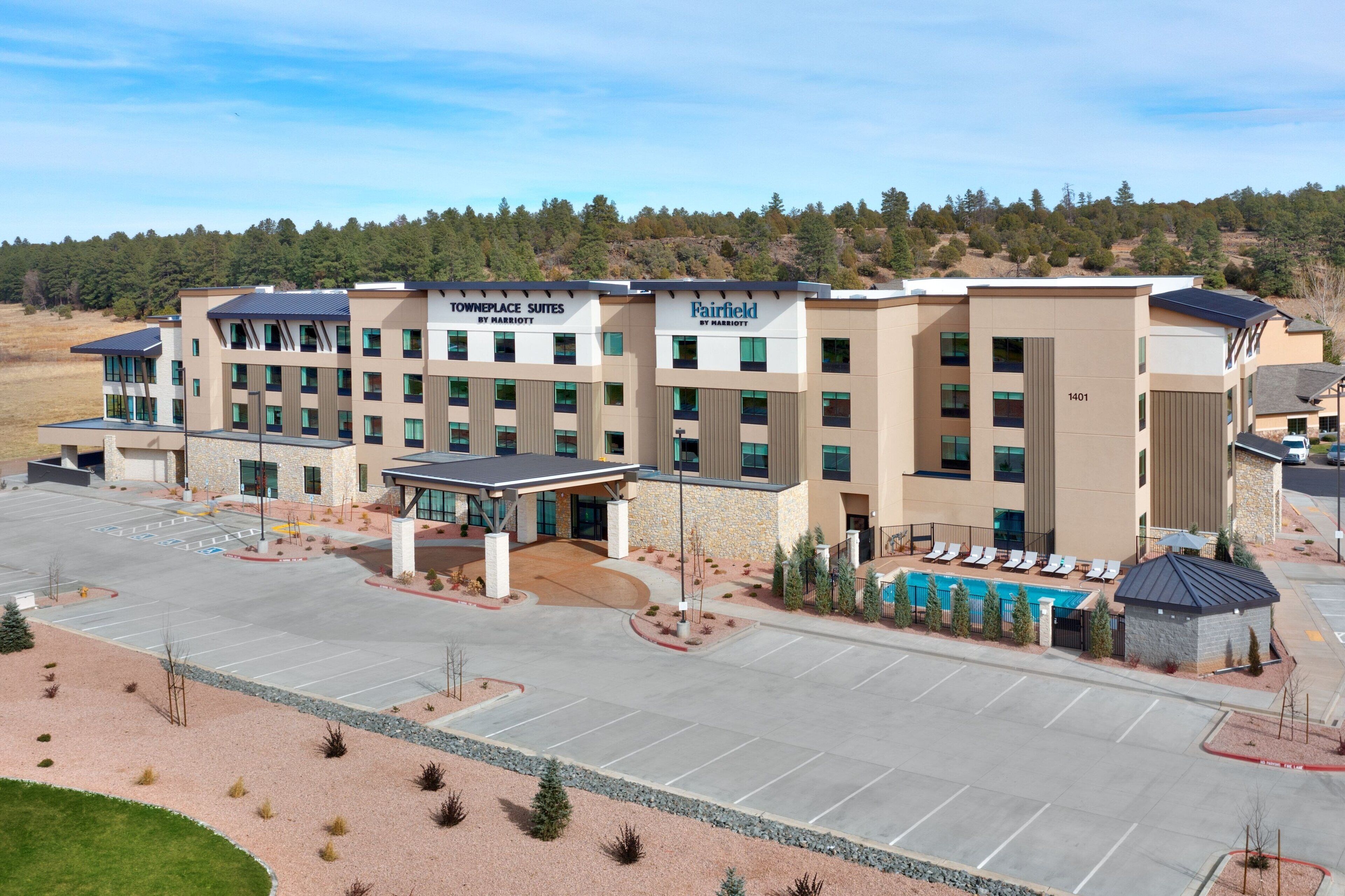 A hotel with multiple floors, a parking lot, and a swimming pool area.