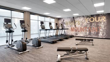Un gimnasio con cintas de correr, elípticas y bancos de pesas.
