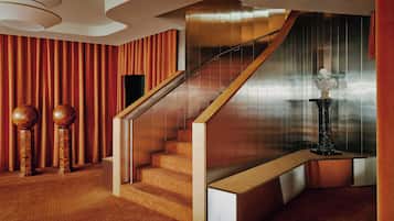 Una escalera moderna con barandilla de madera, una estatua de mármol y un papel tapiz estampado.