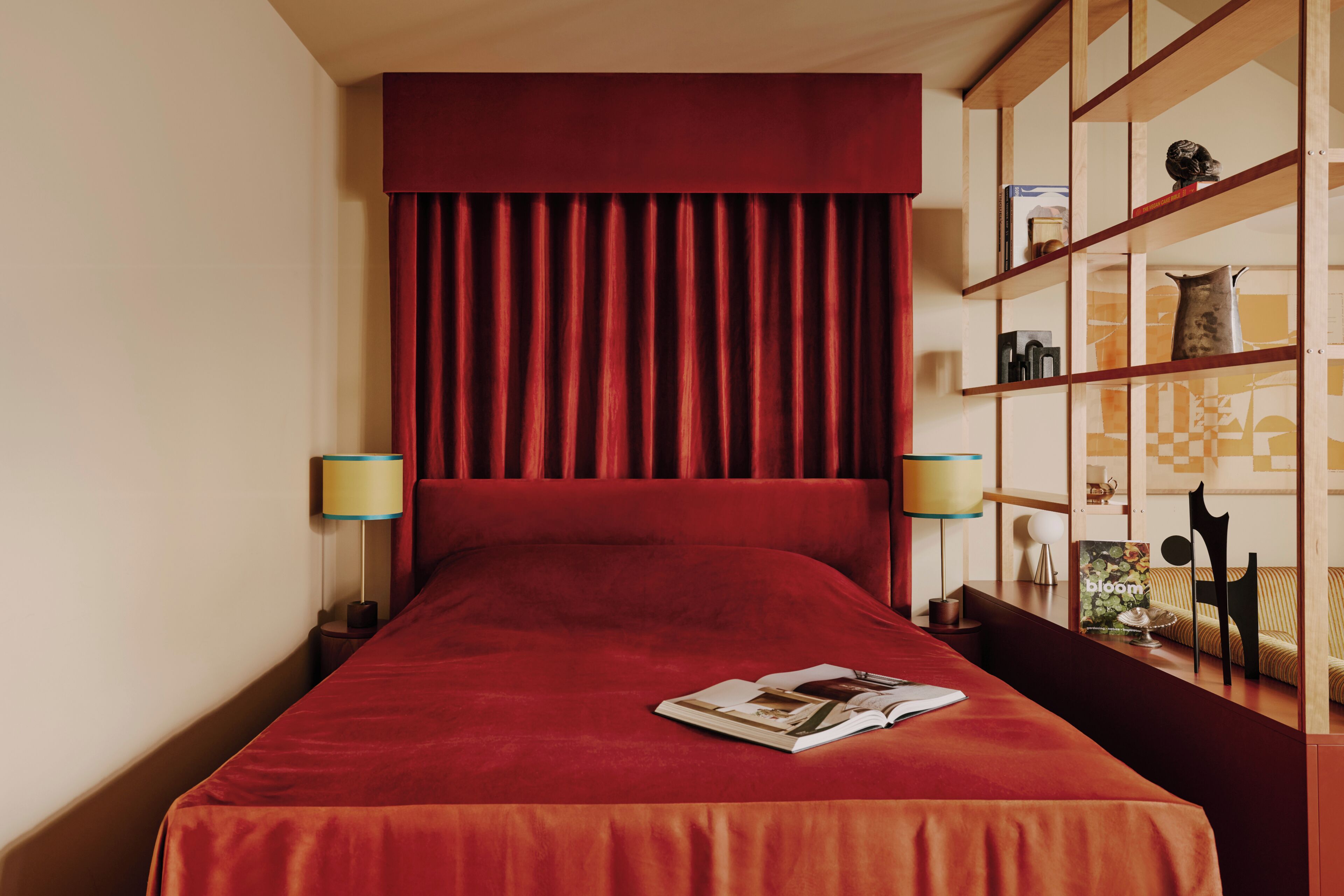 A hotel room with a large bed, a bookshelf, and two bedside lamps.