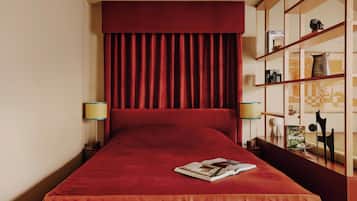 A hotel room with a large bed, a bookshelf, and two bedside lamps.