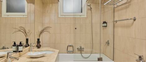 Un baño con dos lavamanos, una bañera y una ducha.