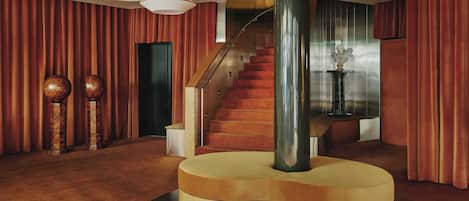 Un vestíbulo espacioso con una imponente escalera, una mesa redonda de madera y una columna grande.