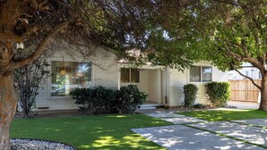 A single-story house with a front porch, a well-maintained lawn, and a driveway leading to the garage. - Classic Inglewood Gem 3Bed/1Bath w/Jacuzzi (Inglewood)