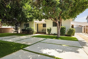 A residential property with a well-maintained lawn, a paved driveway, and a front porch.