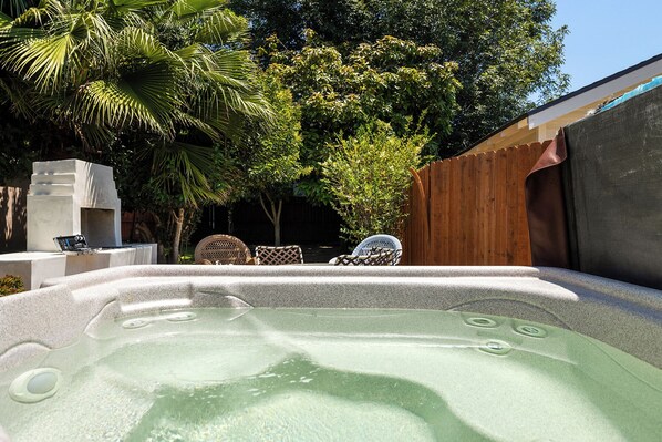 Relax in a serene hot tub surrounded by lush greenery and a natural backdrop.