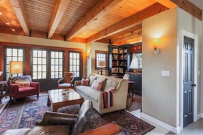 Ein gemütliches Wohnzimmer mit Holzboden, einer Couch, einem Couchtisch und einem Bücherregal.