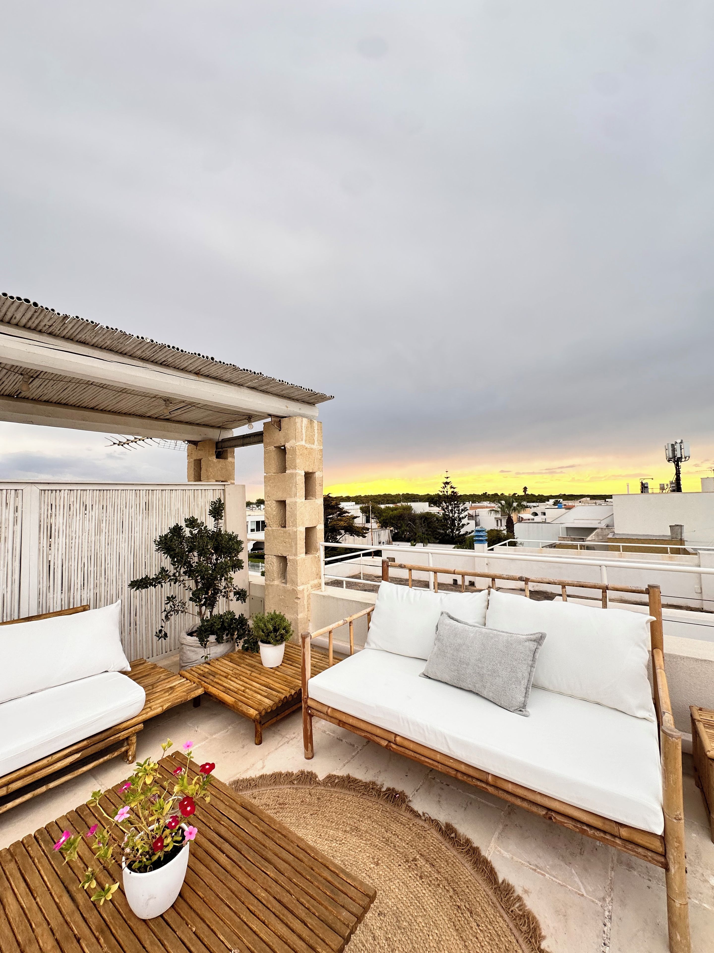 Eine Dachterrasse mit einer Holzbank, einem weißen Sofa und einem Blumentopf.