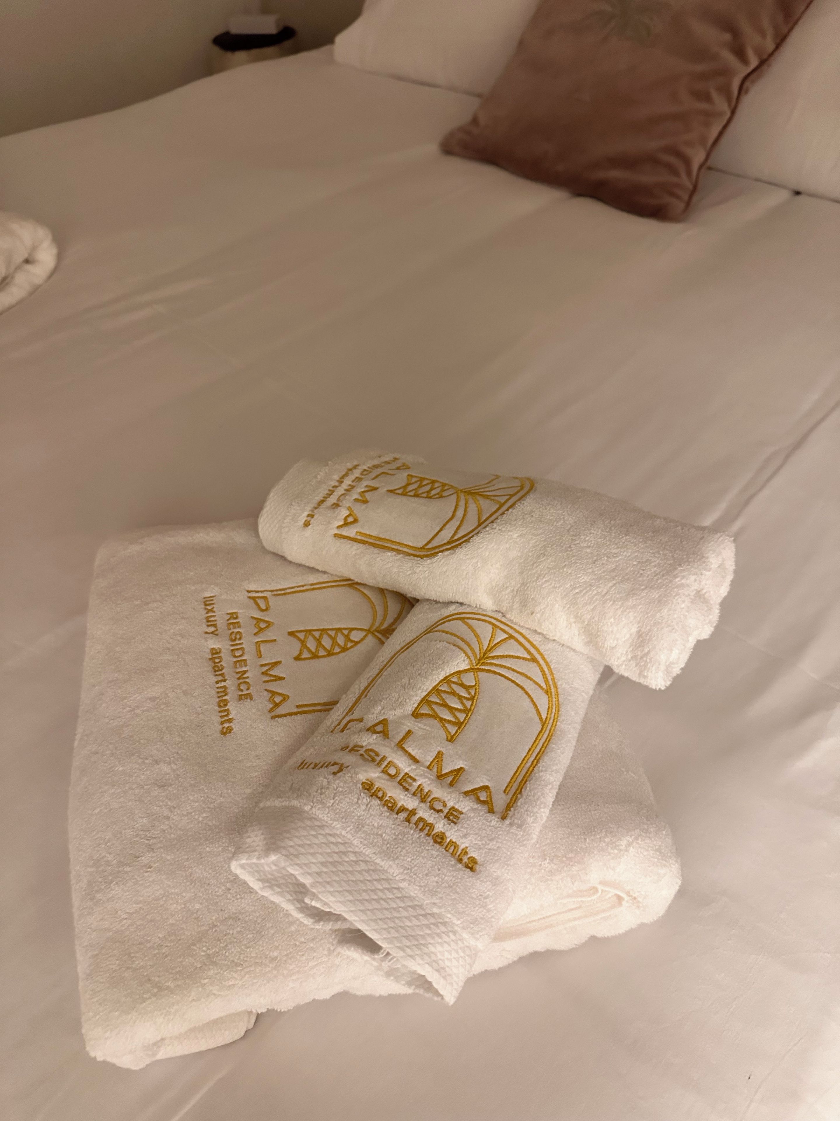 Un lit avec du linge de lit blanc et deux serviettes ornées d’un motif en relief.