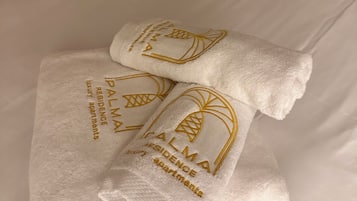 Un lit avec du linge de lit blanc et deux serviettes ornées d’un motif en relief.