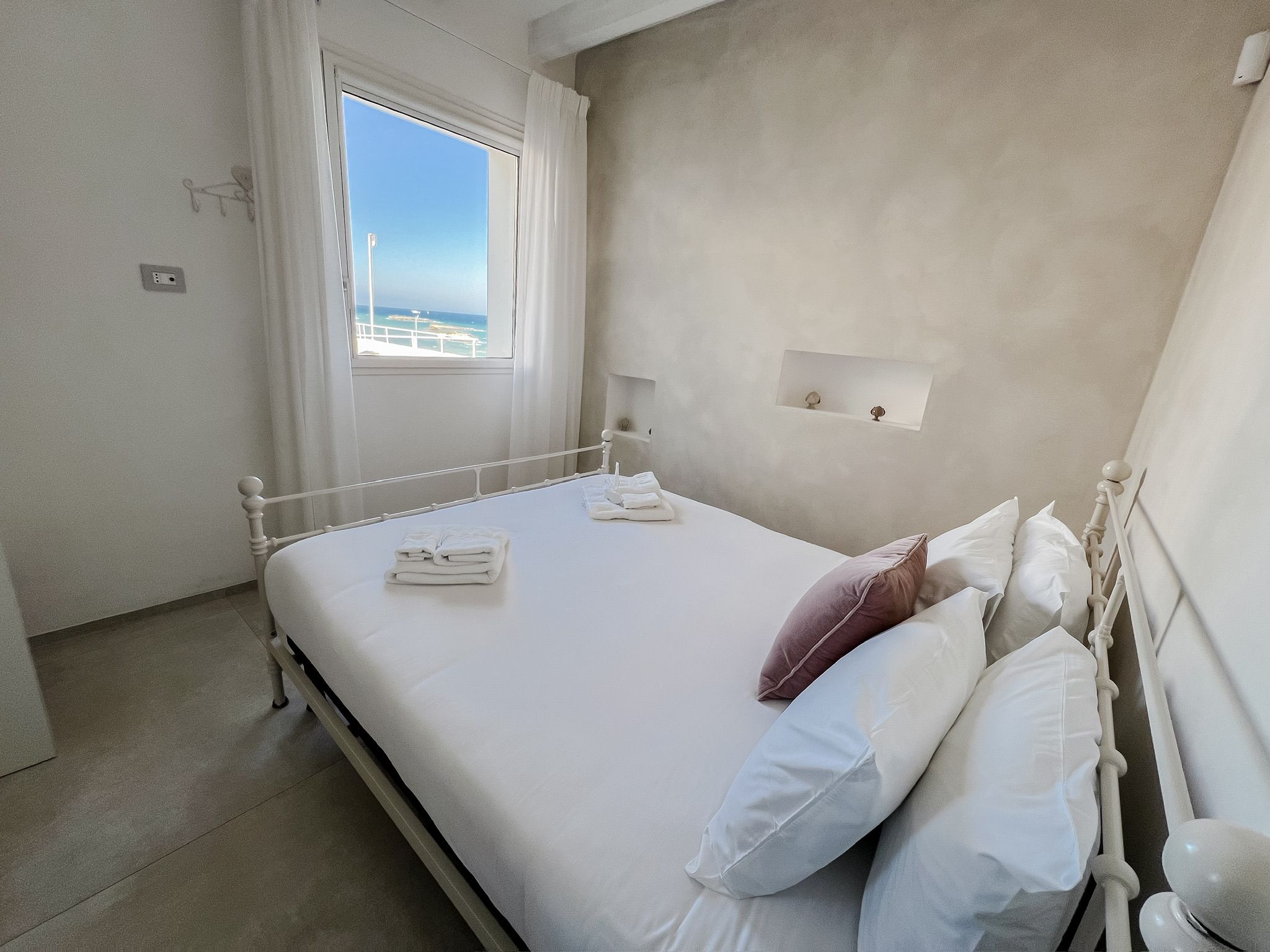 Ein Schlafzimmer mit Bett, Fenster, Nachttisch und Wandregal.