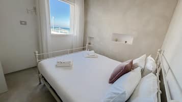Ein Schlafzimmer mit Bett, Fenster, Nachttisch und Wandregal.