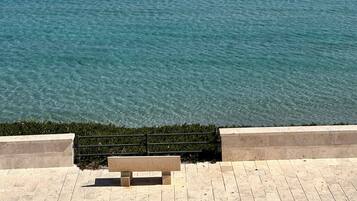 Uma passarela pavimentada com um banco e vista para o mar.