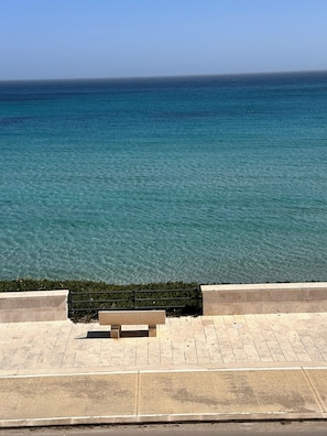 Une promenade dallée avec un banc et une vue sur la mer.