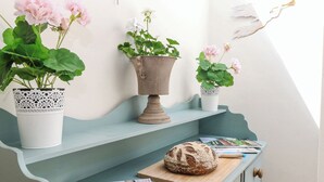 Un comptoir de cuisine avec une miche de pain, une planche à découper et un magazine. Trois plantes en pot sont posées sur le comptoir.