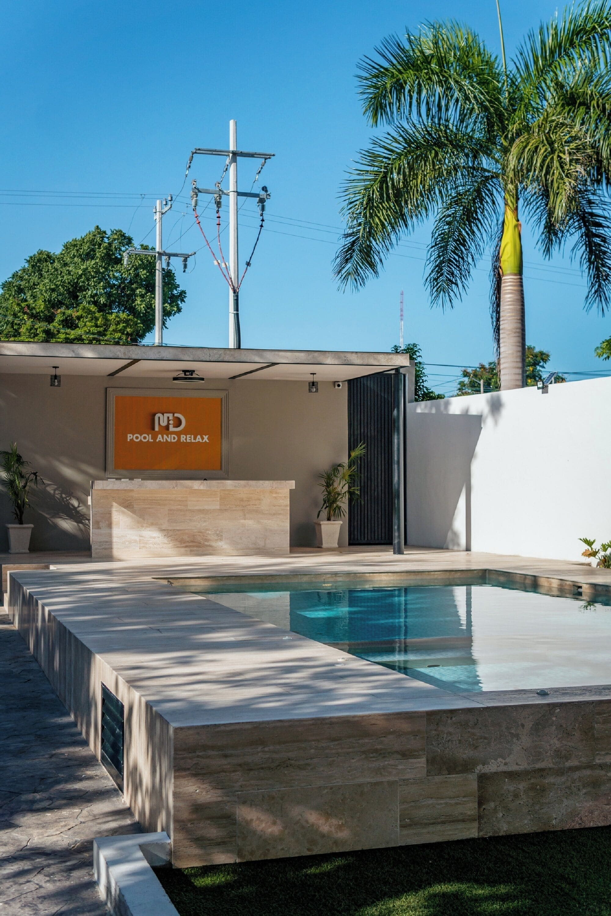 A modern pool area with a sign reading "POOL AND RELAX".