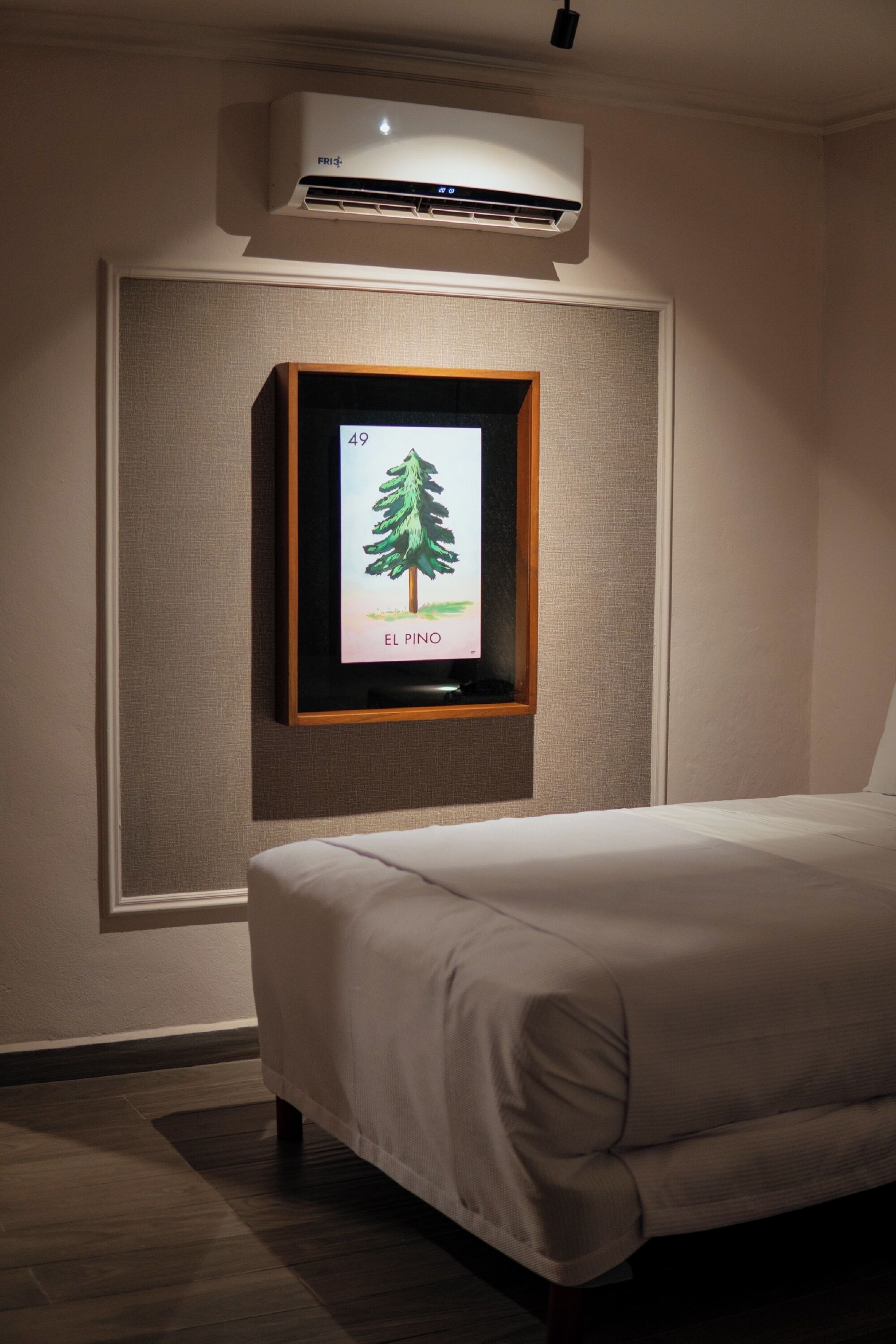 Un dormitorio con cama, un cuadro con un árbol y un equipo de aire acondicionado.