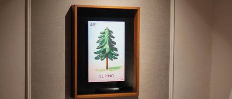 Un dormitorio con cama, un cuadro con un árbol y un equipo de aire acondicionado.