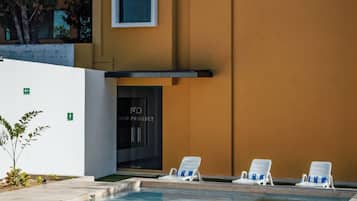 Un edificio moderno con piscina, sillas de descanso y un cartel que dice "MID PROJECT".