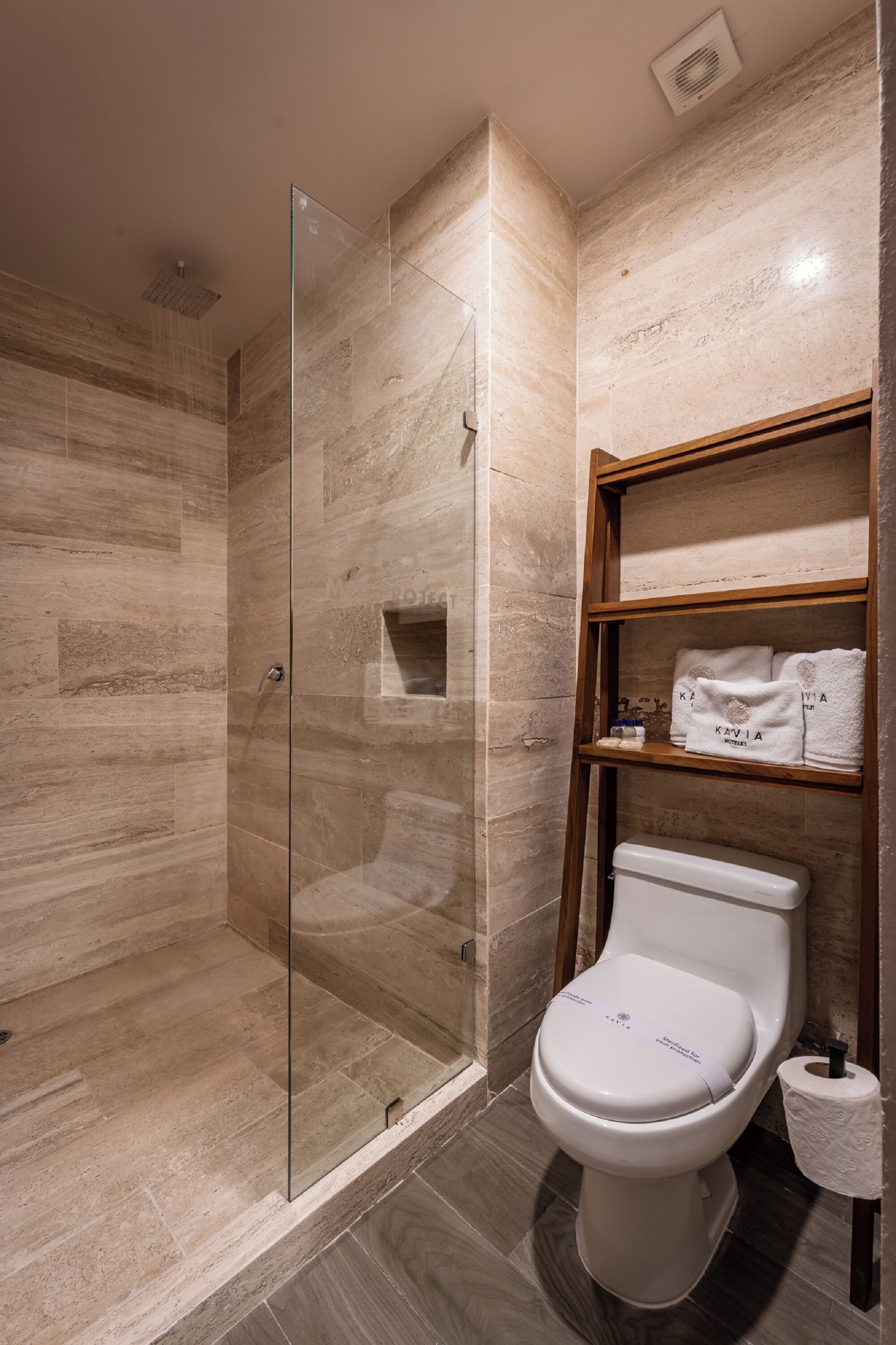 Un baño moderno con ducha de vidrio, inodoro y repisa con toallas.